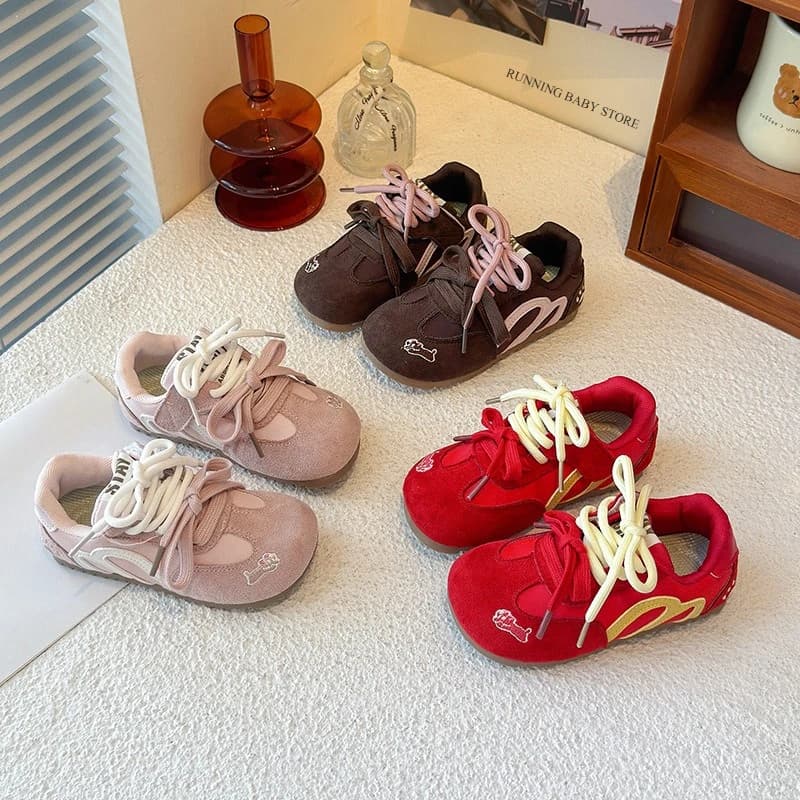 Tênis esportivos infantis rosa, marrom e vermelho com detalhes em branco, preto e amarelo, dispostos em um fundo branco