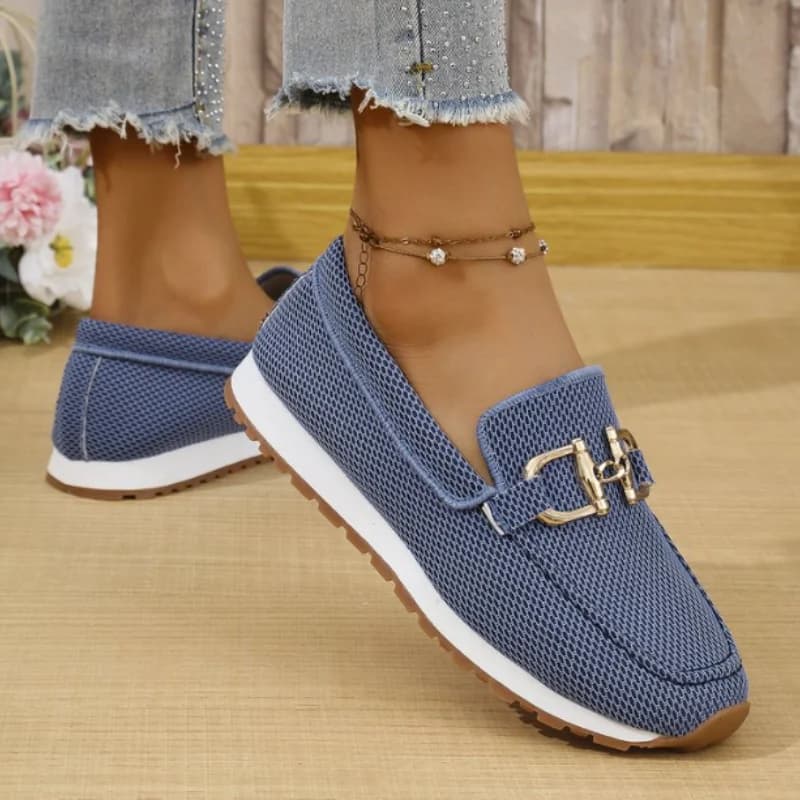 Tênis feminino azul marinho com textura de malha e fivelas douradas, sola branca e marrom