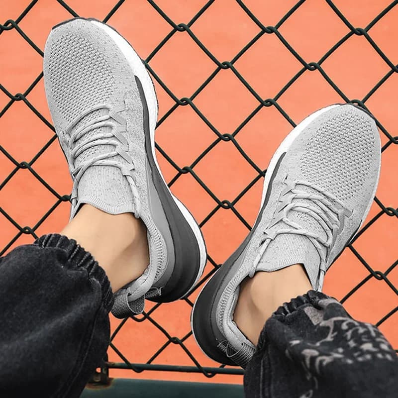 Tênis esportivo masculino cinza e preto com sola branca e design respirável