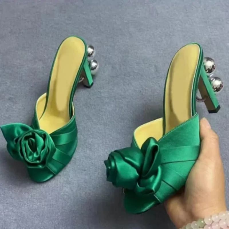Sandálias mule de salto alto verdes com bico aberto, laço em formato de flor e salto com bolas metálicas
