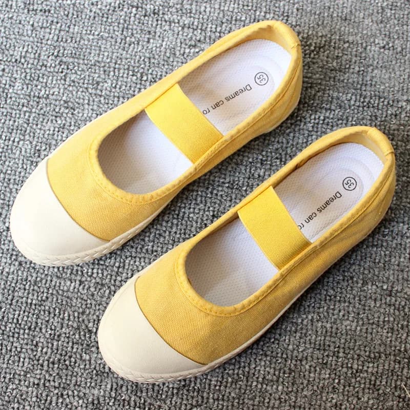 Tênis slip-on feminino amarelo em lona com sola plana branca e elástico no peito do pé
