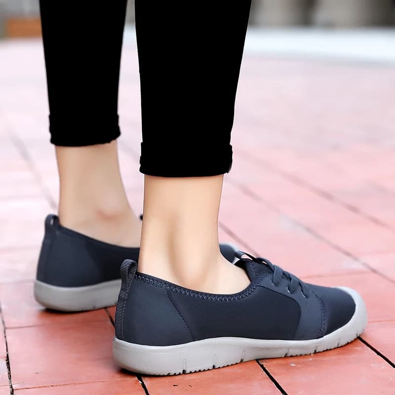 Tênis feminino azul escuro slip-on com sola cinza e cordões pretos, confortável e antiderrapante.