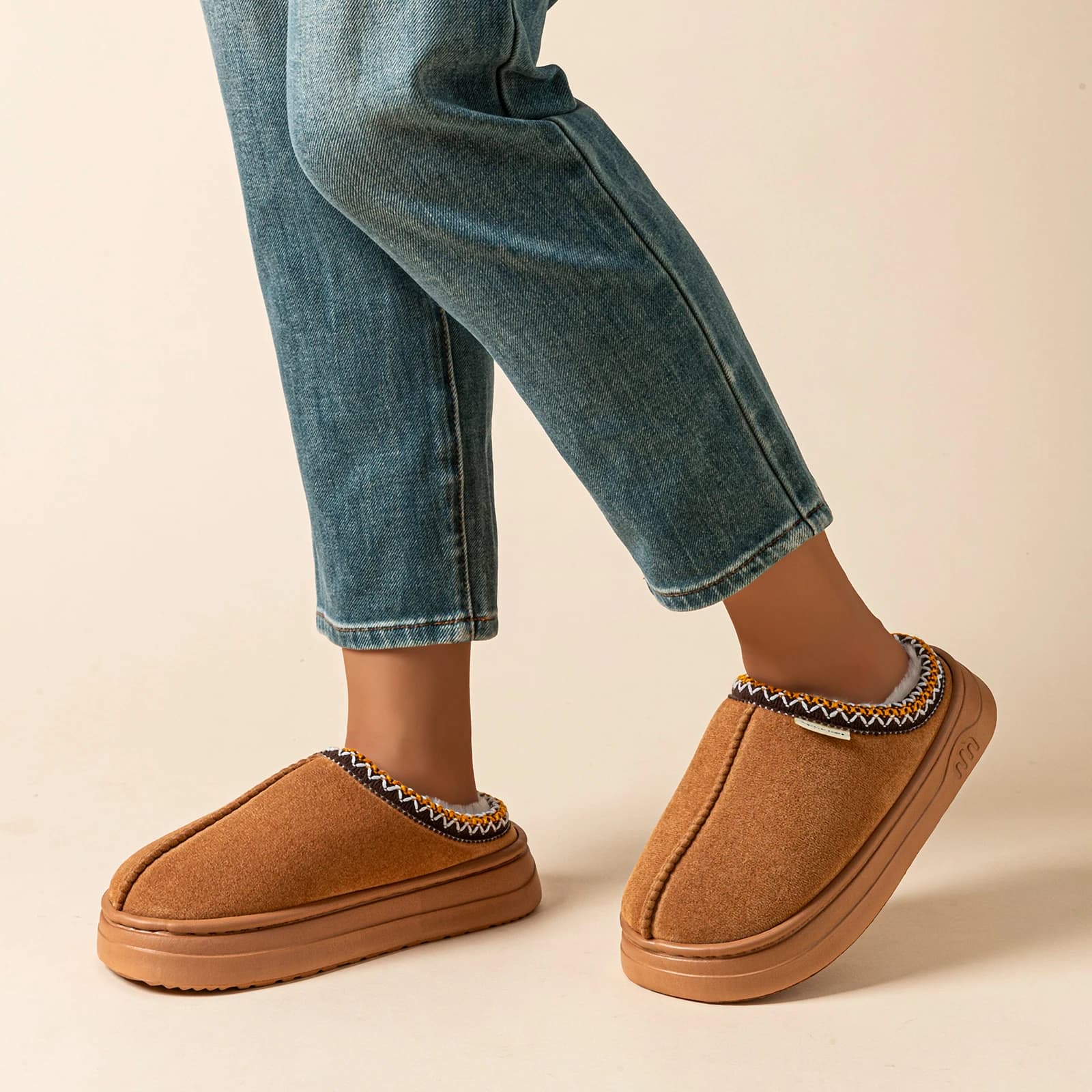Chinelos femininos de pelúcia marrom sendo usados com calça jeans, conforto para inverno