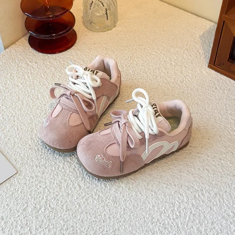 Trê pares de tênis esportivos infantis rosa e marrom com detalhes em branco e preto, dispostos em um fundo branco