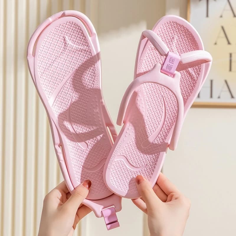Chinelos de viagem dobráveis antiderrapantes rosa claro sendo segurados para mostrar flexibilidade