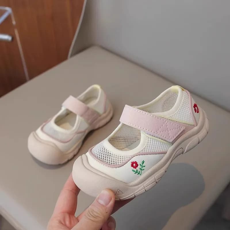 Menina usando sandálias infantis brancas com detalhes em rosa e azul, antiderrapantes e respiráveis