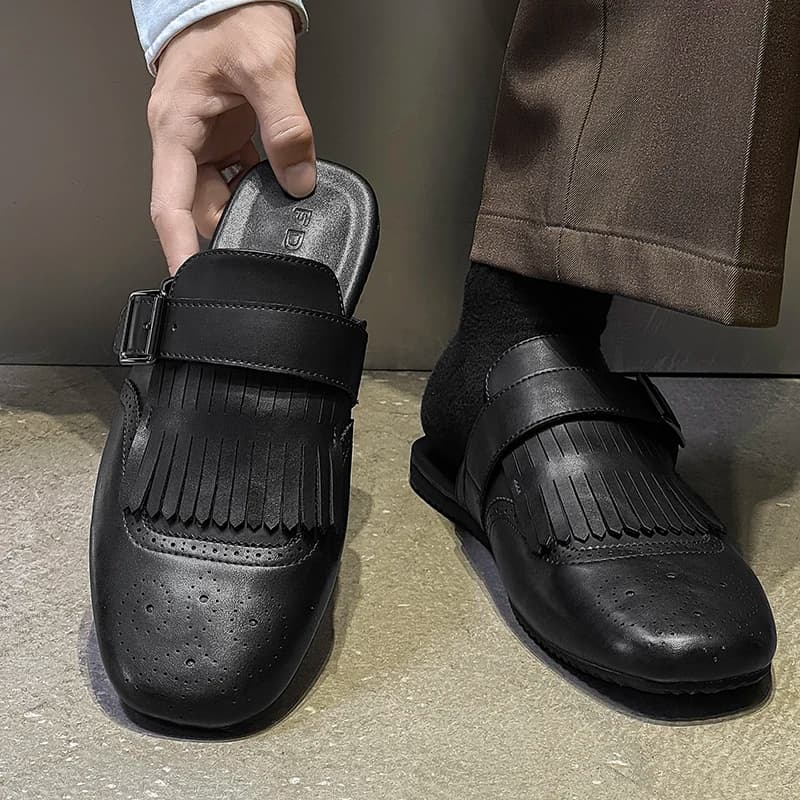 Mocassim masculino preto de couro com tassel sendo calçado, detalhe da palmilha e fivela
