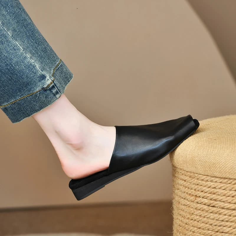 Mule feminina preta de couro com bico coberto e solado preto, estilo casual