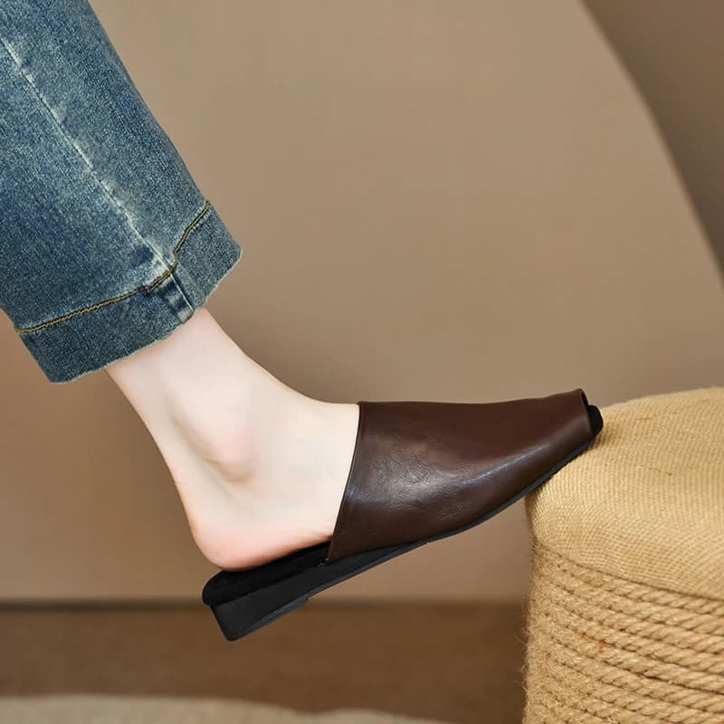 Mule feminina marrom de couro com bico coberto, solado preto e estilo minimalista