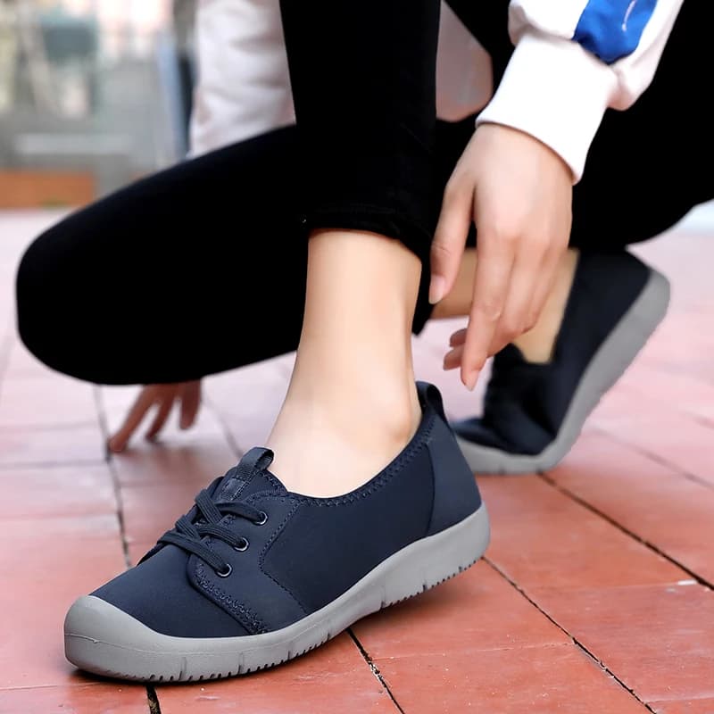 Tênis feminino azul escuro slip-on com sola cinza e cordões pretos, confortável e antiderrapante.