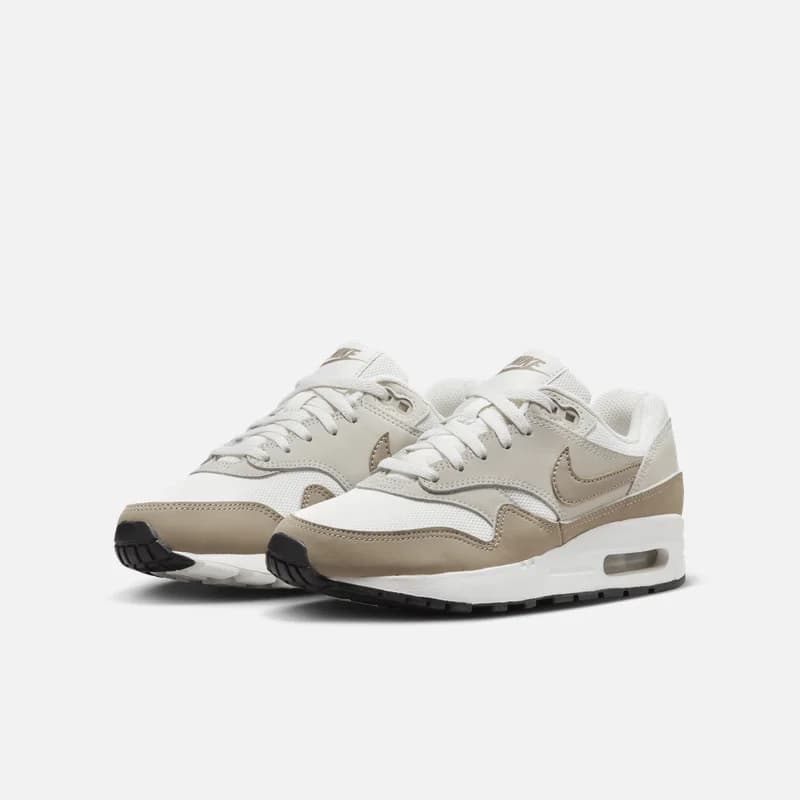 Par de tênis Nike Air Max 1 femininos estilo retro bege e branco com solado preto e branco