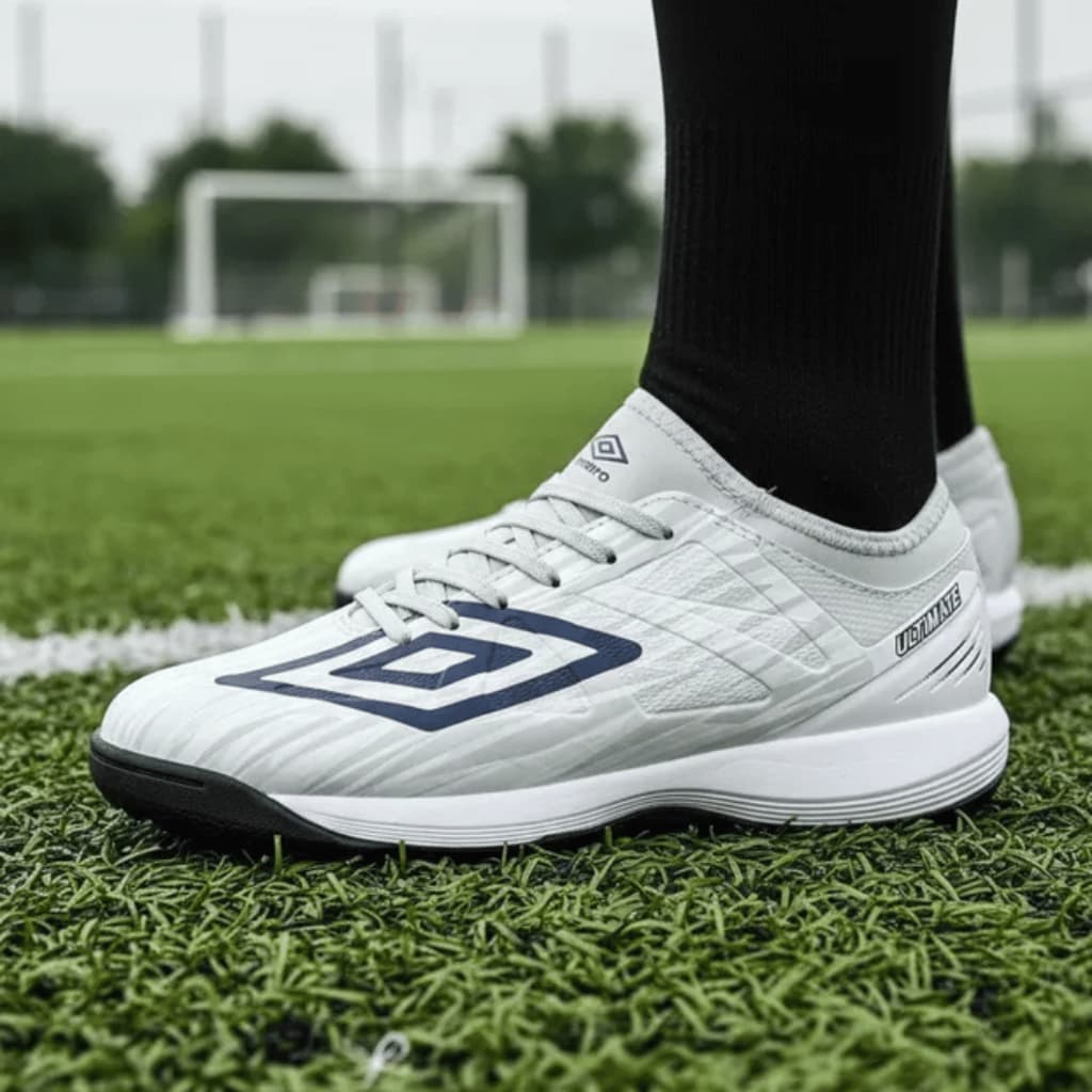 Chuteira infantil Umbro Ultimate Jr branca e azul em campo de futebol