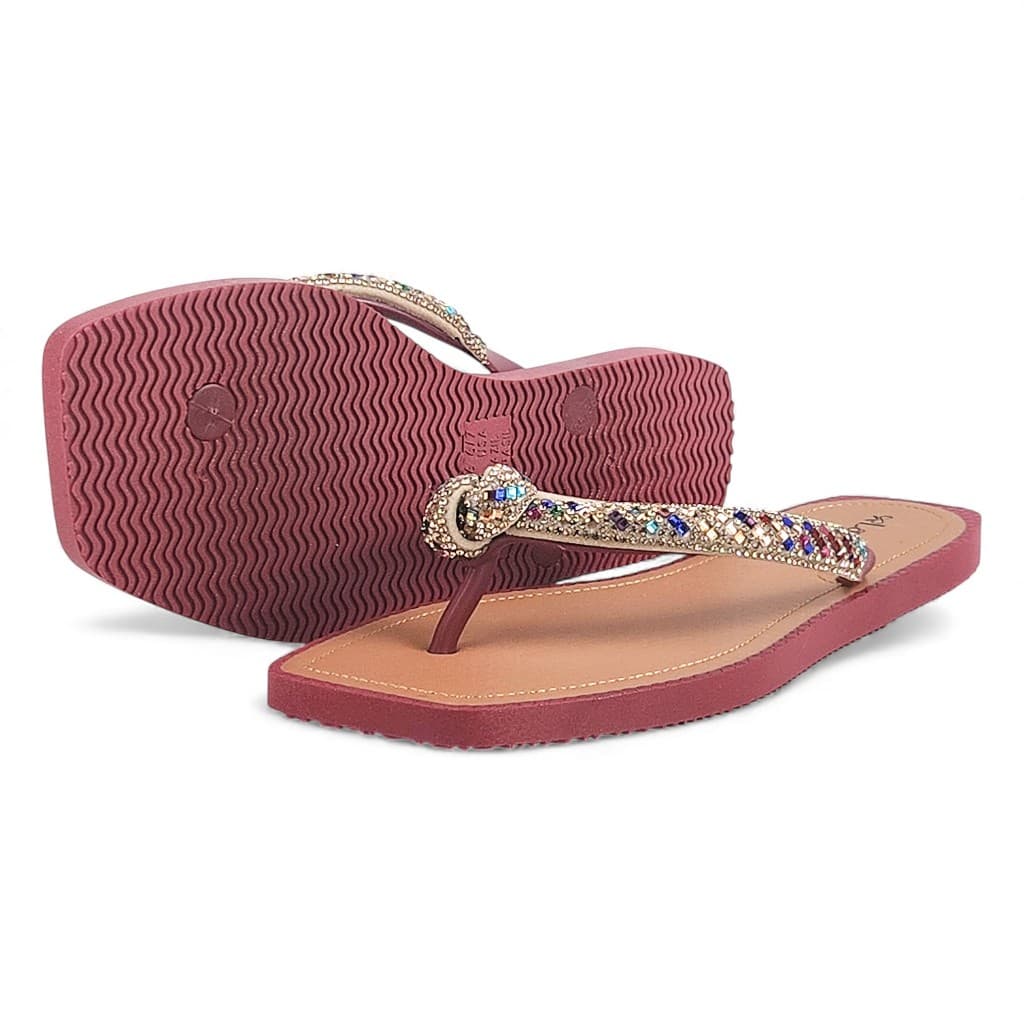 Sandálias femininas confortáveis com tiras brilhantes em nó, cor rosa, sola vermelha, textura ondulada, fundo branco.