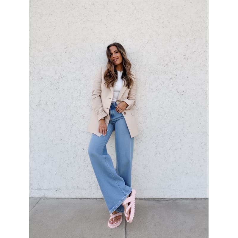 Mulher usando sandália rosa de tiras finas, calças jeans e blazer bege