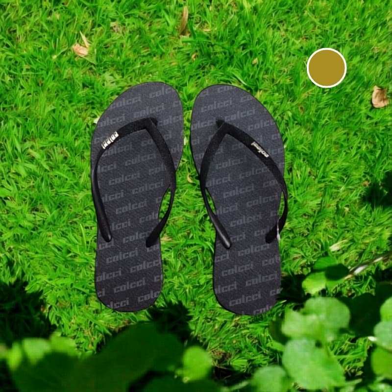 Chinelos Colcci pretos com estampa em relevo em fundo verde gramado
