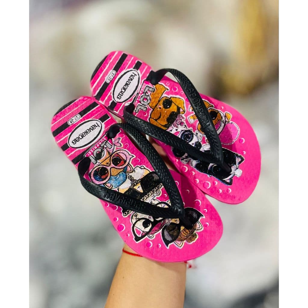 Sandálias infantis rosa com estampa de personagens de animais, cachorro e abelha, tiras pretas, fundo com listras pretas e branco, design confortável.