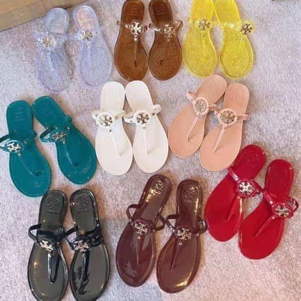 Sandálias transparentes e coloridas da marca Tory Burch em fundo branco