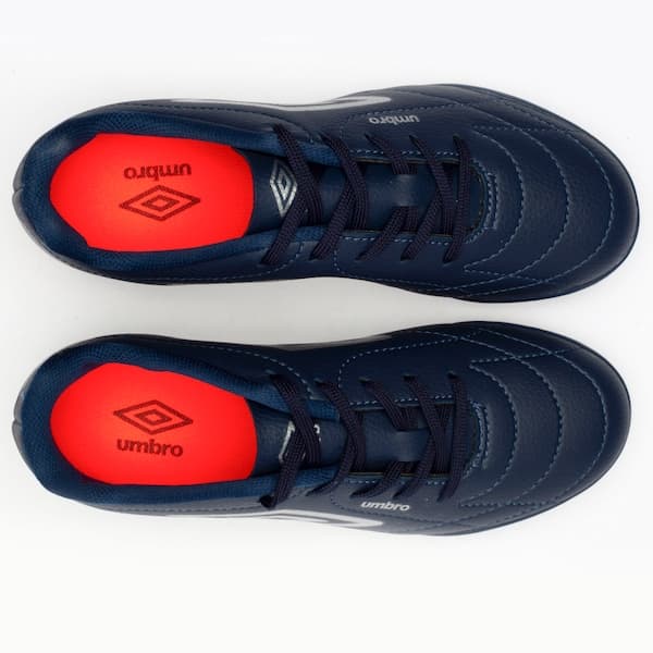 Tênis de futebol Umbro Class Society Kids, azul marinho com detalhes vermelhos e sola de borracha.