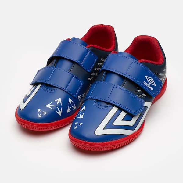 Par de chuteiras futsal infantil Umbro Velocita, azul e vermelho, com logo branco.