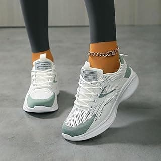 Tênis esportivos brancos com detalhes verdes em piso cinza