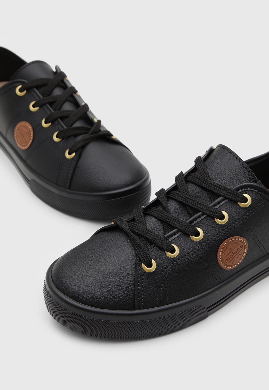 Par de tênis feminino casual Moleca preto com detalhes dourados e logo.